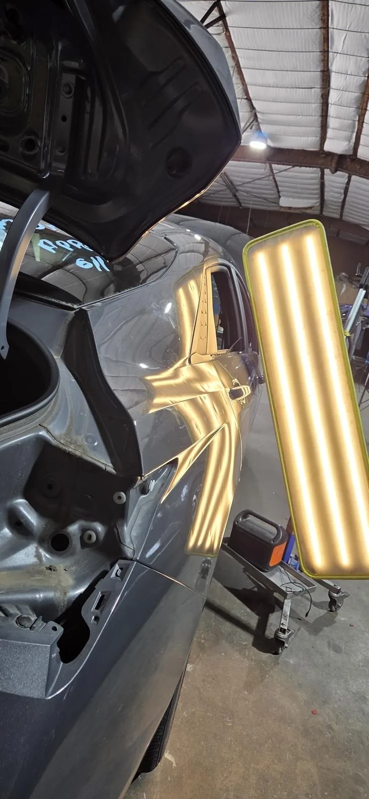 Specialized PDR inspection lighting deployed against a vehicle panel to reveal dents during the repair process